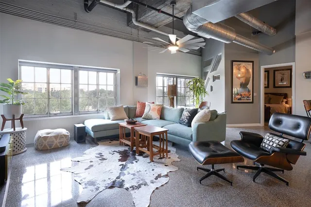 a living room with furniture hard wood floor and a floor to ceiling window