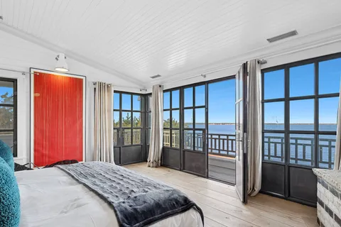 a bedroom with a balcony a bed and a dresser next to a window