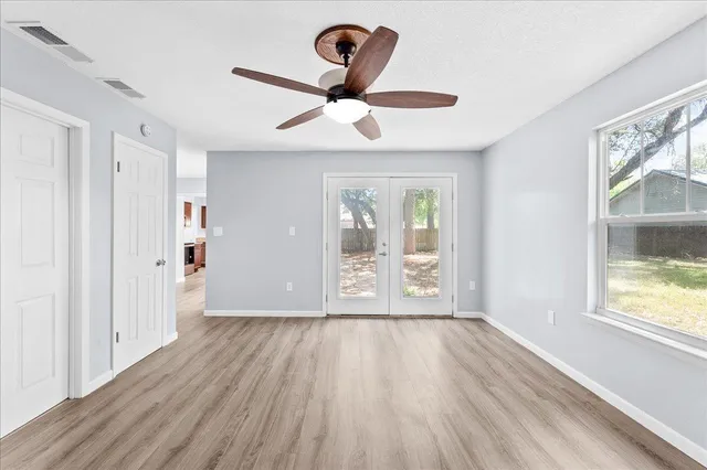 a view of an empty room with wooden floor and a window