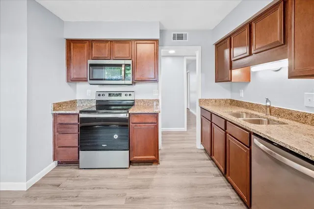 a kitchen with stainless steel appliances granite countertop a stove a sink and a microwave