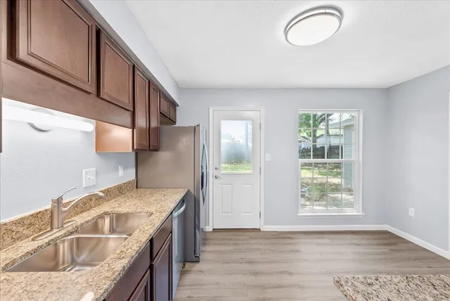 a kitchen with granite countertop a sink a stove and wooden cabinets