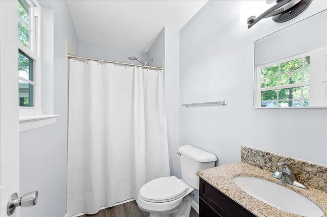 a bathroom with a granite countertop toilet and a sink