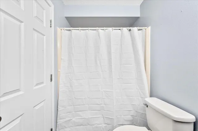 a white toilet sitting next to a white curtain