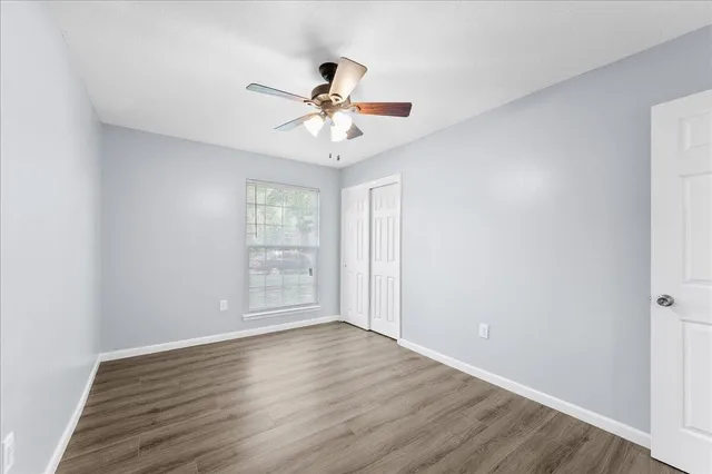 a view of an empty room with wooden floor and a window