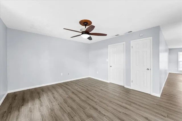 a view of a room with wooden floor and a ceiling fan