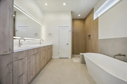 a spacious bathroom with a double vanity sink a mirror and a bathtub