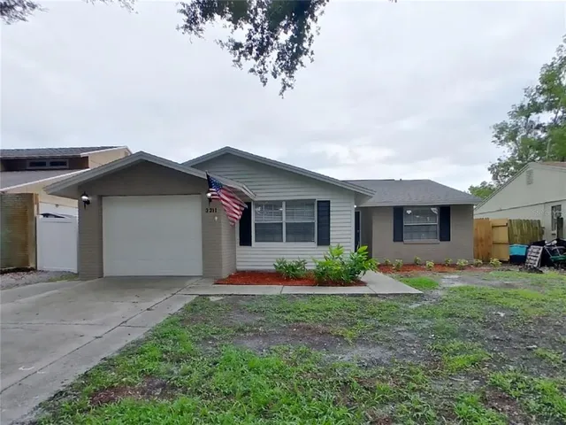 a front view of house with yard and trees in the background