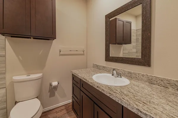 a bathroom with a granite countertop sink a toilet and mirror