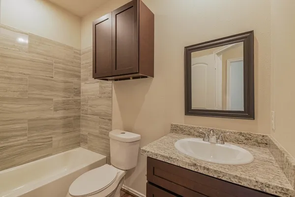 a bathroom with a granite countertop toilet sink and mirror