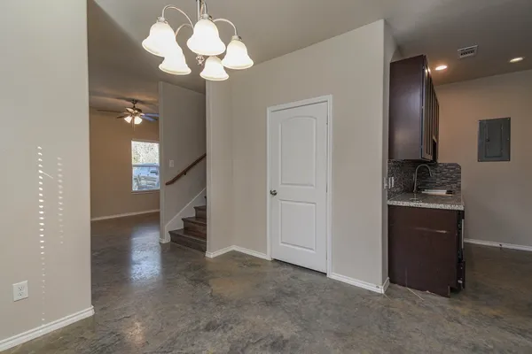 a view of an empty room with a fireplace and a chandelier fan