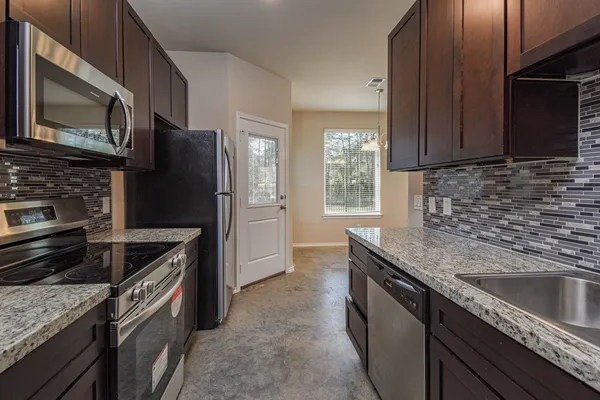 a kitchen with granite countertop a sink stove and refrigerator