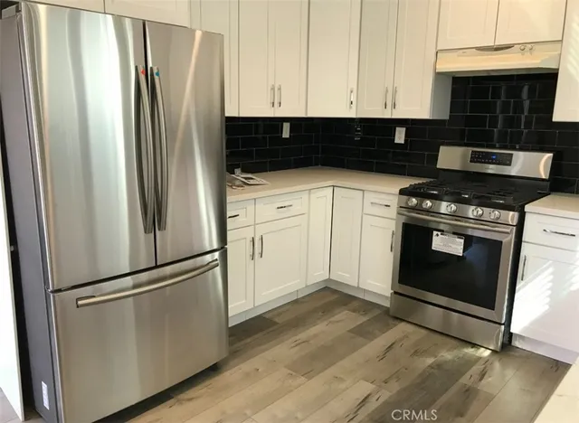 a kitchen with white cabinets and stainless steel appliances
