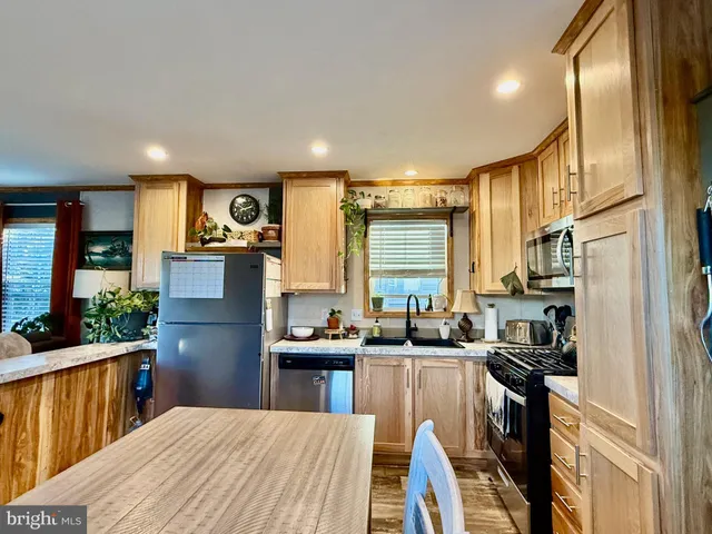 a kitchen with stainless steel appliances kitchen island granite countertop a sink refrigerator and cabinets