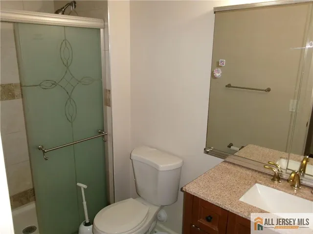 a bathroom with a granite countertop sink toilet and a mirror