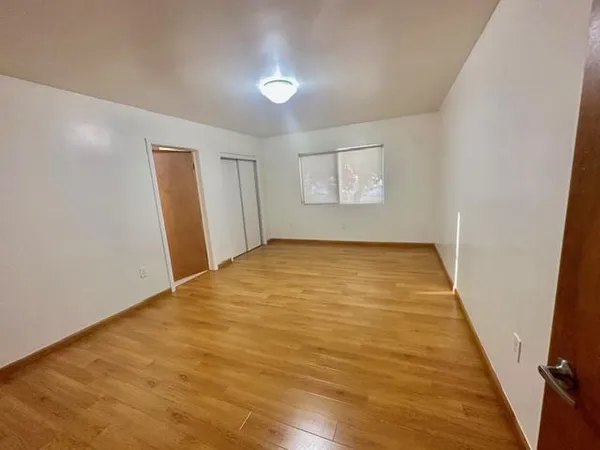 an empty room with wooden floor and windows