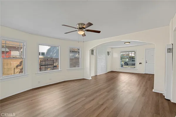 a view of an empty room with a window and wooden floor