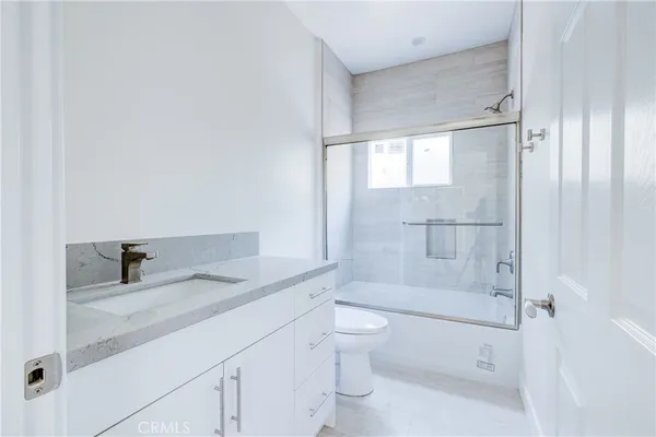 a bathroom with a granite countertop sink a toilet and shower