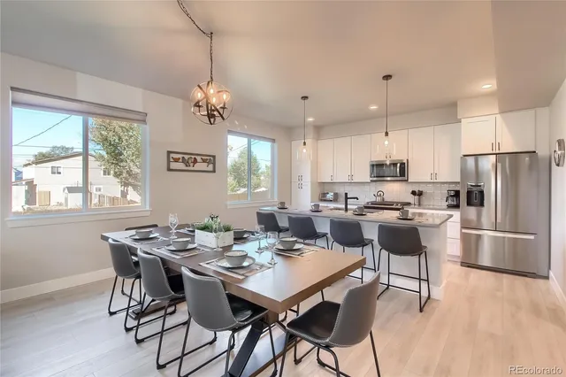 a kitchen with stainless steel appliances kitchen island granite countertop a dining table chairs refrigerator and sink