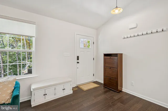 a view of an empty room with wooden floor and windows