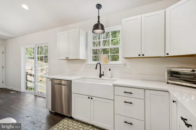 a kitchen with stainless steel appliances granite countertop a sink dishwasher a stove and a window with wooden floor