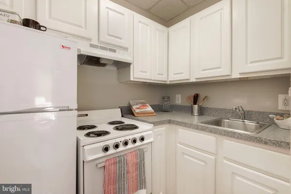 a kitchen with granite countertop white cabinets and white appliances