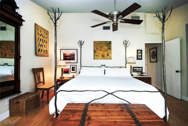 a bedroom with a bed and dresser with wooden floor