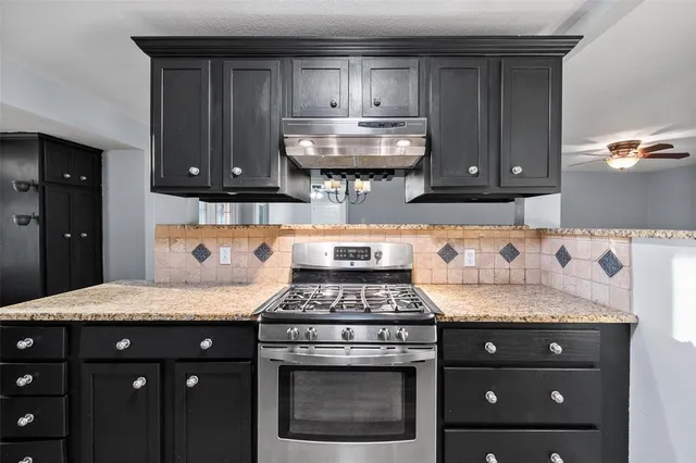 a kitchen with granite countertop a sink a stove and cabinets