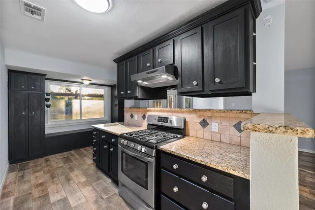 a kitchen with stainless steel appliances granite countertop wooden cabinets stove top oven and sink