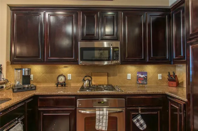 a kitchen with granite countertop stainless steel appliances wooden cabinets and a sink