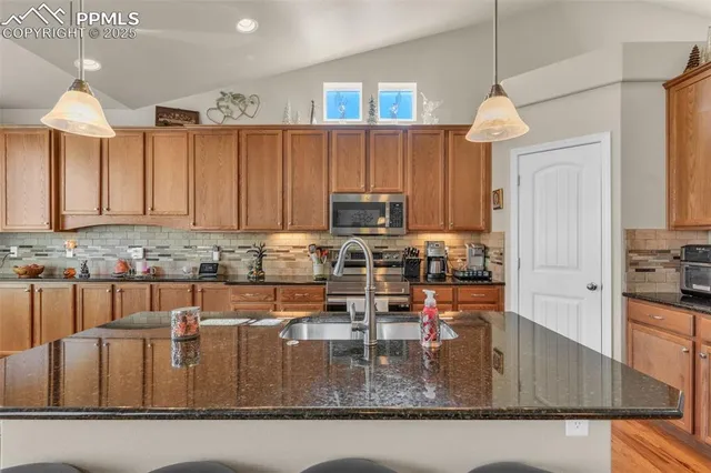 a kitchen with kitchen island granite countertop a table chairs microwave and cabinets