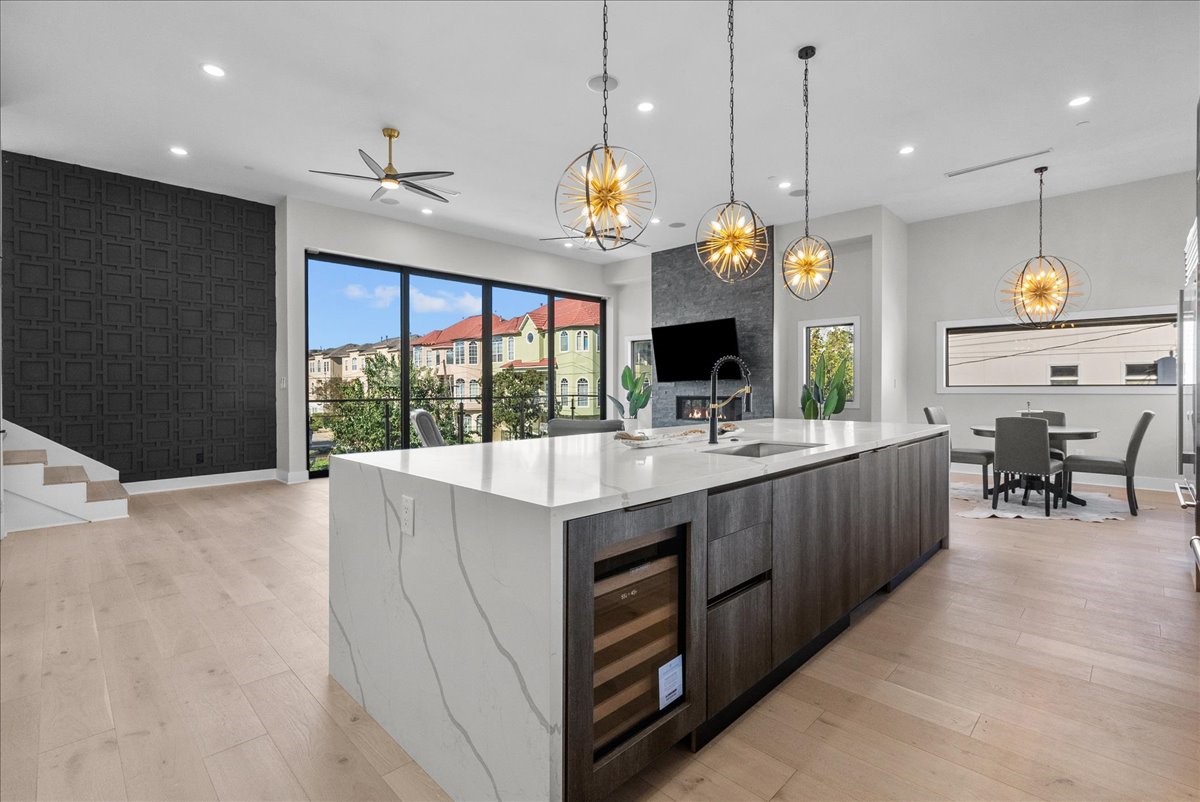 516 Reinerman Street Houston, TX 77007 - Photo 13 of 42 This modern open-concept kitchen and living space features sleek cabinetry, a large marble island, and striking pendant lights. Expansive windows offer abundant natural light and views, while a stylish fireplace adds warmth. Elegant dining and seating areas make it perfect for entertaining.