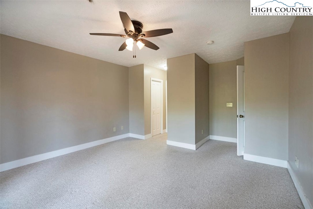 446 Peaceful Haven Drive, Unit 811 Boone, NC 28607 - Photo 16 of 31 an empty room with a ceiling fan and carpet