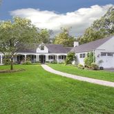 a front view of a house with a garden and trees