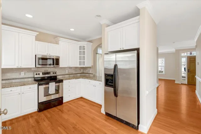 a kitchen with stainless steel appliances granite countertop a refrigerator a stove and a sink with wooden floor
