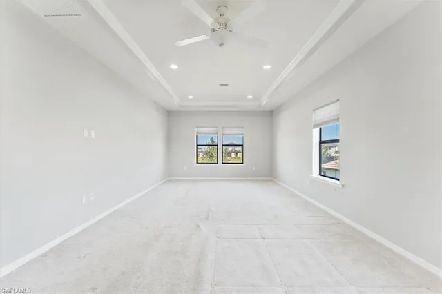 an empty room with windows and ceiling fan