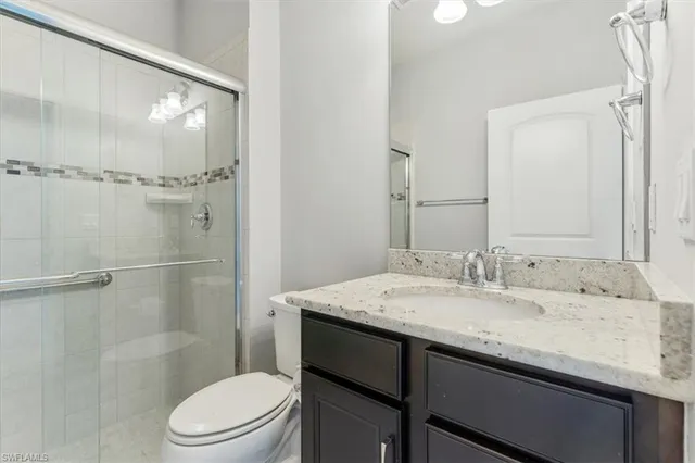 a bathroom with a granite countertop sink toilet a mirror and shower