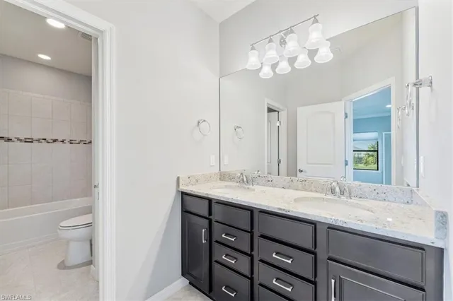 a bathroom with a granite countertop sink a toilet and a mirror