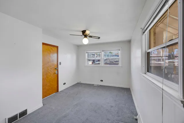 an empty room with windows and fan