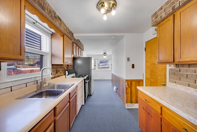a kitchen with a sink a counter top space stainless steel appliances cabinets and a window