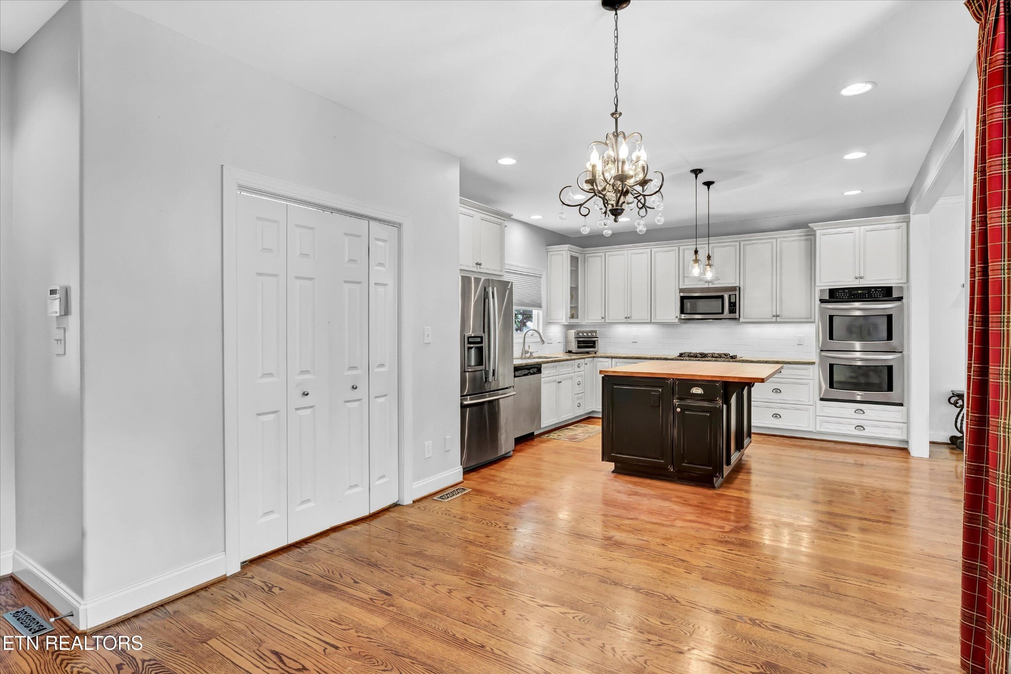 140 Ootsima Way Loudon, TN 37774 - Photo 10 of 31 a large kitchen with kitchen island a stove a refrigerator a sink dishwasher a oven with white cabinets and wooden floor