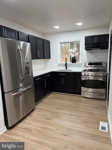 a large kitchen with stainless steel appliances granite countertop a stove a refrigerator and a microwave