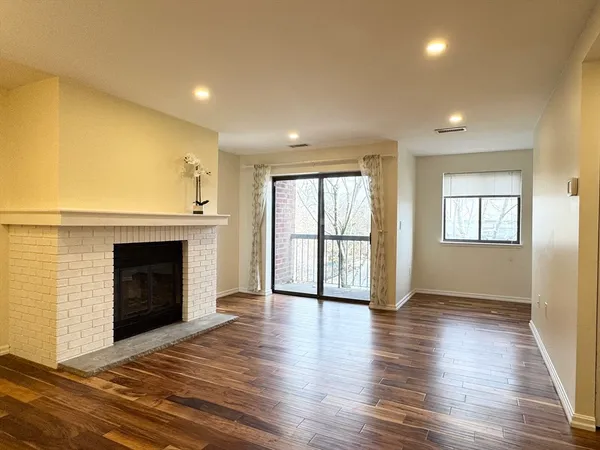 an empty room with wooden floor fireplace and windows