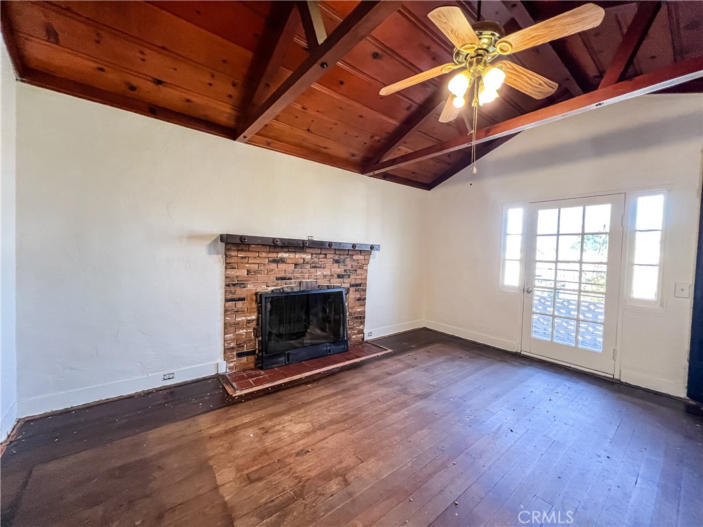 506 Desnok Street Needles, CA 92363 - Photo 14 of 70 an empty room with wooden floor fireplace and windows