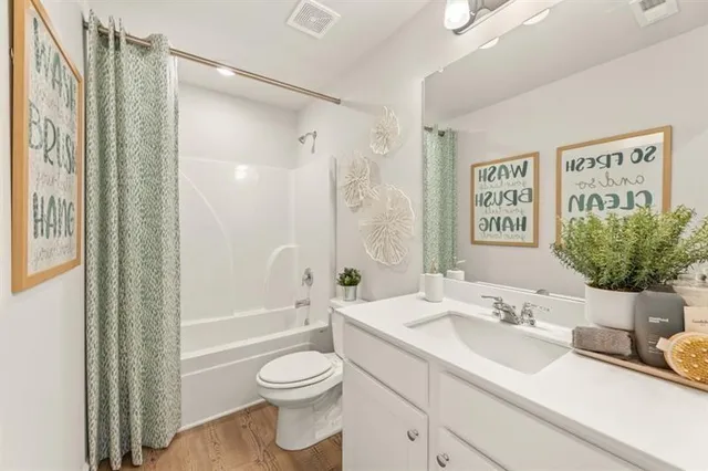 a bathroom with a granite countertop sink toilet a large mirror a shower and a bathtub
