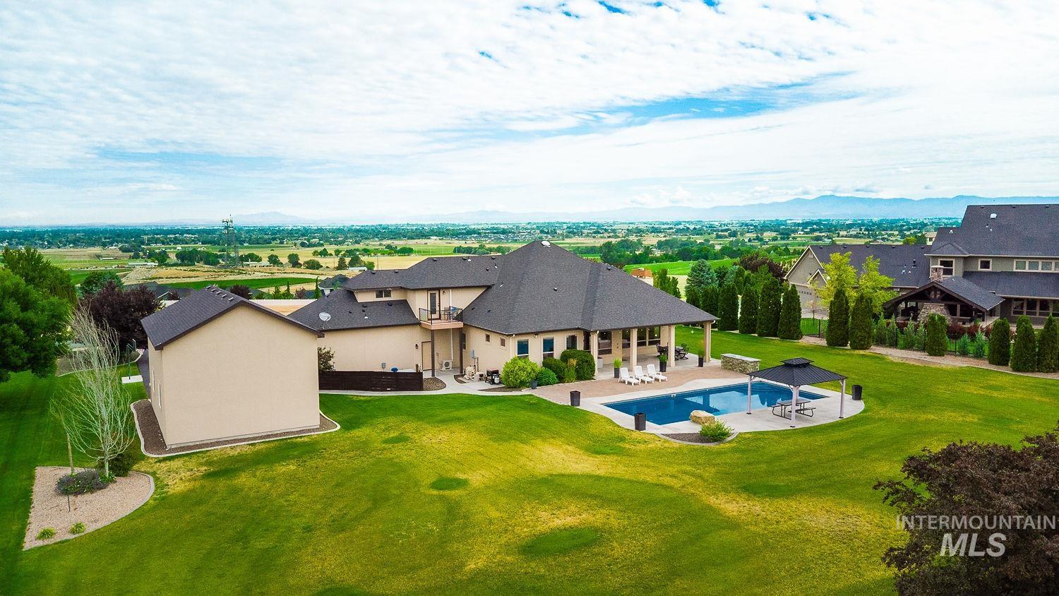 8077 Star Pass Ridge Road Nampa, ID 83686 - Photo 4 of 37 Expansive rear yard featuring an in-ground swimming pool, a covered patio, and a separate structure with a dark roof