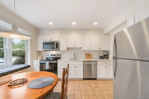 a kitchen with stainless steel appliances granite countertop a refrigerator a stove top oven a sink dishwasher and white cabinets with wooden floor