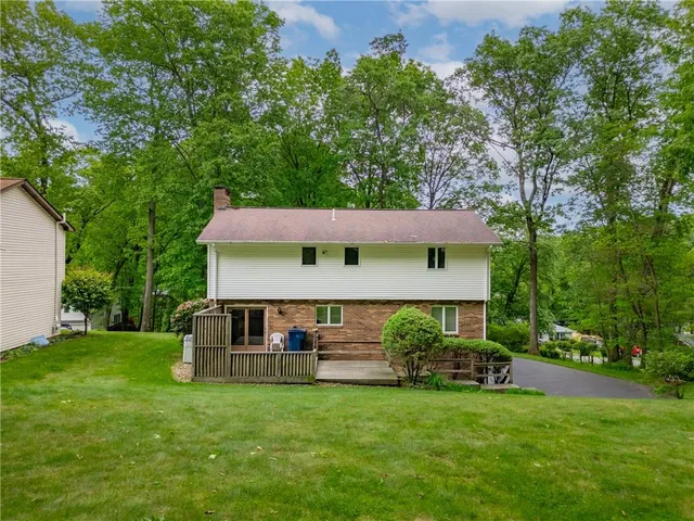 a front view of a house with a garden and trees