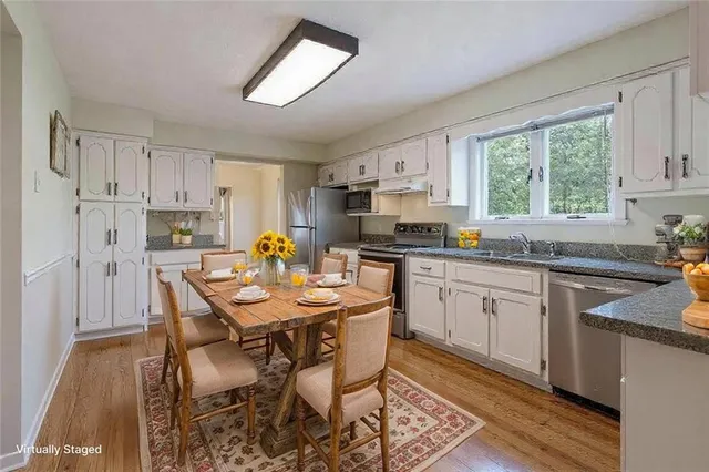 a kitchen with stainless steel appliances kitchen island granite countertop a table chairs sink and cabinets