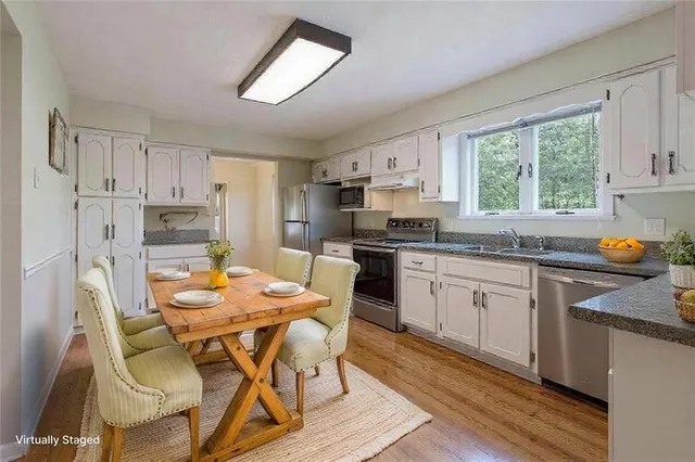 a kitchen with stainless steel appliances granite countertop a stove a sink dishwasher a refrigerator with a dining table and chairs