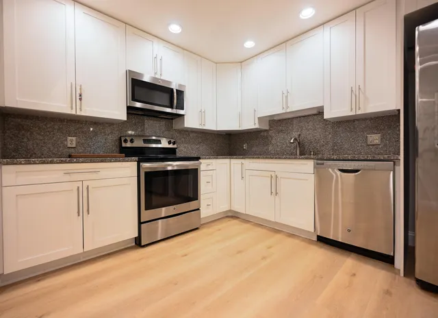 a kitchen with white cabinets stainless steel appliances and sink